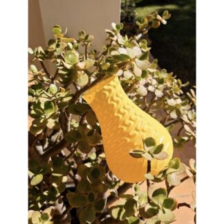 3D printed yellow dragon vase outdoors in a plant